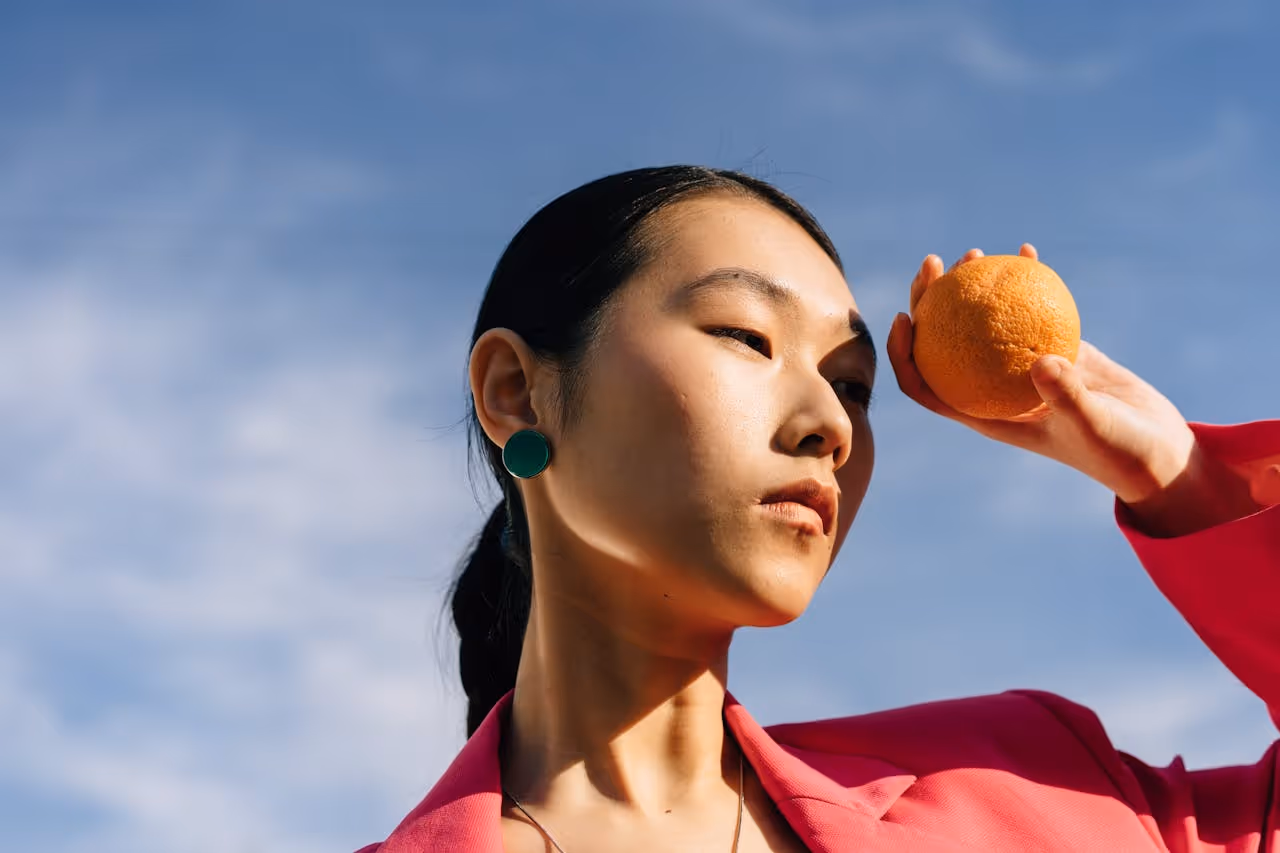 Woman in a pink suit holding an orange.